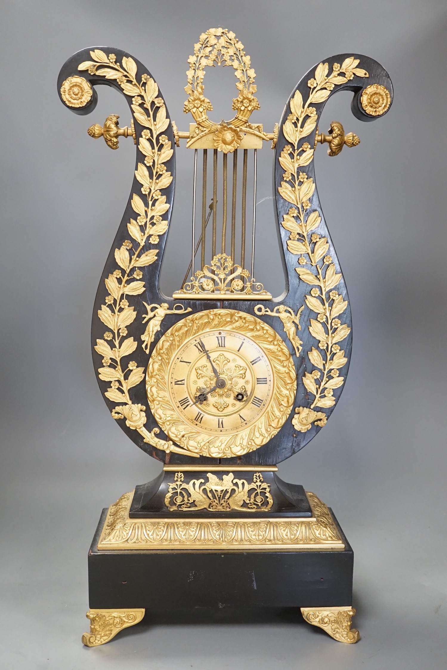 A 19th century French black lyre shaped clock, with gilt leaf decoration on scroll feet, 57cm tall